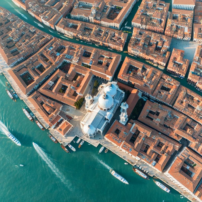 从空中俯瞰威尼斯三角形地段，大运河、生机勃勃的陶土屋顶、突出的白顶教堂、水上贡多拉以及熙熙攘攘、五彩缤纷的城市景观尽收眼底