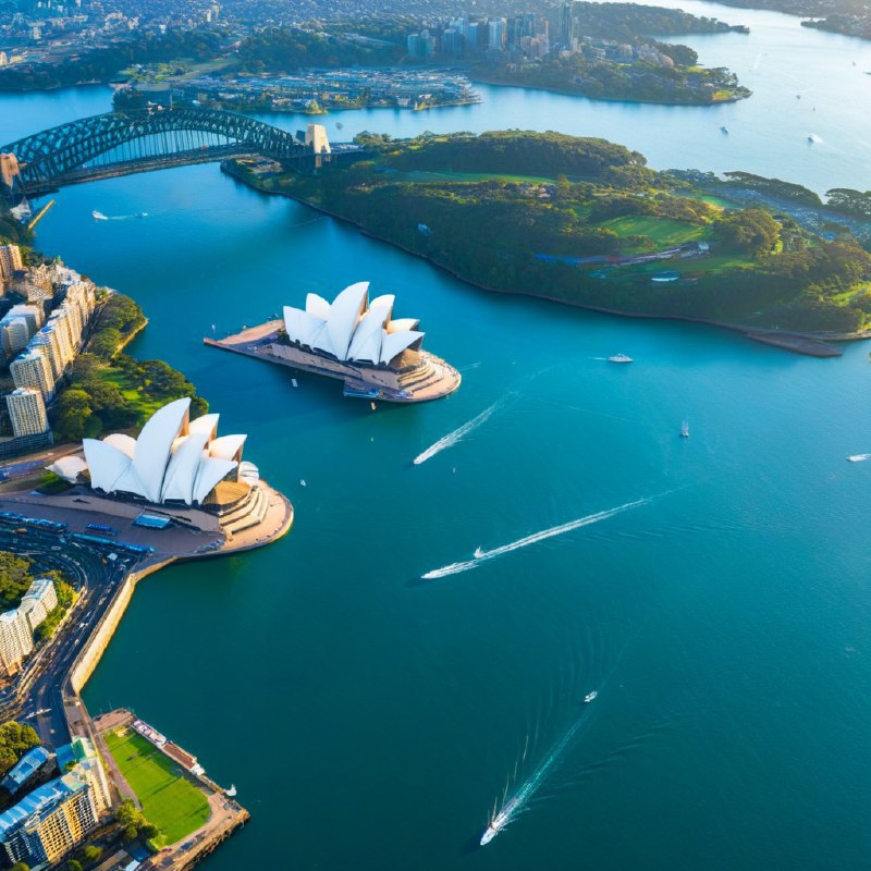 #Bing_Wallpaper"一幅令人叹为观止的悉尼港鸟瞰图，展示了位于澳大利亚新南威尔士州的标志性建筑悉尼歌剧院和海港大桥沐浴在黄昏的金色光辉中