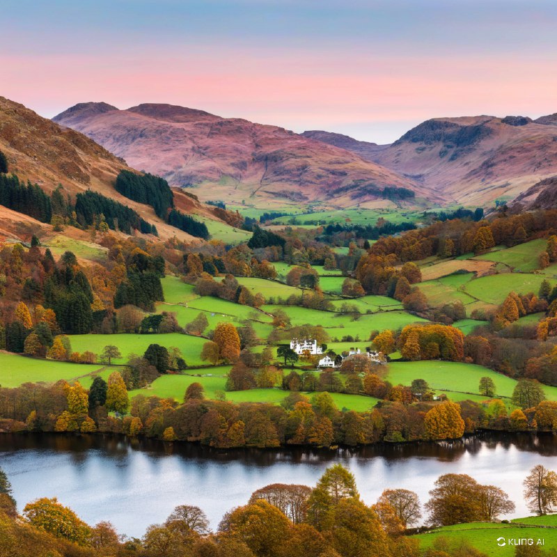 秋季的英格兰湖区格拉斯米尔风景宁静如画，平静的湖面倒映着秋叶的缤纷色彩，翠绿的草地和连绵起伏的山丘在粉色的天空下交相辉映