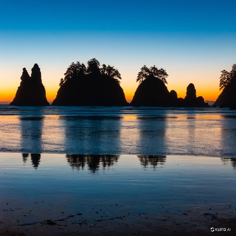 奥林匹克国家公园宁静海滩上令人惊叹的日落，岩石海垛的剪影，从深蓝过渡到暖橙色的生机勃勃的天空，平静倒影的海水，宁静祥和的氛围